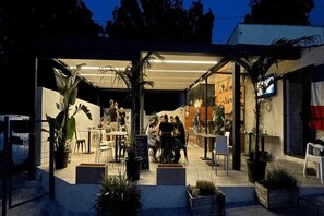 Enjoy casual dining in a stylish urban setting with a bar area and outdoor seating surrounded by lush greenery.