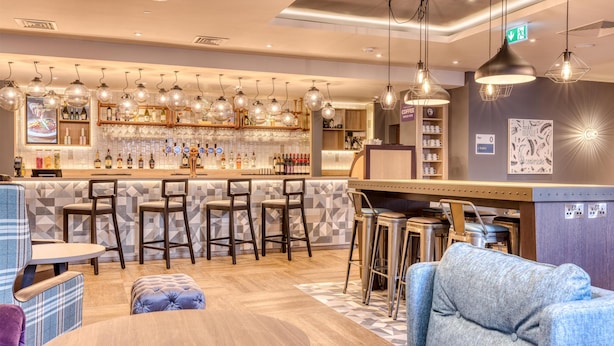 A bar area with stools, a counter, and hanging lights. - Premier Inn Cork City Centre (Cork)