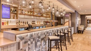 A bar area with a counter, stools, and hanging light fixtures. - Premier Inn Cork City Centre (Cork)
