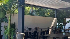 An outdoor cafe with tables and chairs, surrounded by potted plants and a chalkboard menu. - ZEcamping 3* parc aquatique pet friendly hammam tente clim 33m2 6 pers (Bormes-les-Mimosas)