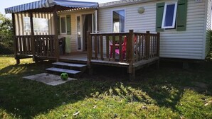 Une maison mobile dotée d’une véranda, d’une petite terrasse et d’une porte d’entrée.