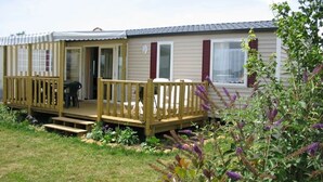 A mobile home with a wooden deck and a covered porch. - ZEcamping 4* animé parc aquatique locatif TV BBQ 32m2 6 pers (Soullans)