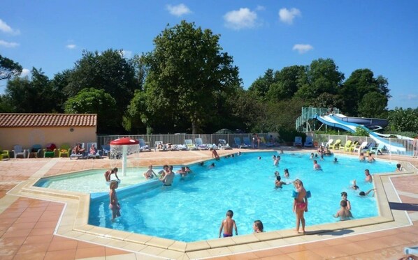 A swimming pool with a water slide and lounge chairs.