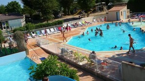 A swimming pool with a water slide, lounge chairs, and a lifeguard stand.