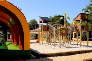 A playground with a slide, climbing structures, and a covered play area. - ZEcamping 4 étoiles familial parc aquatique locatif TV BBQ 40m2 (Soullans)