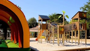A playground with a slide, climbing structures, and a small building with a solar panel. - ZEcamping 4* familial parc aquatique animaux acceptés locatif TV BBQ (Soullans)