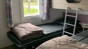 A dormitory room with a bunk bed, a window with curtains, a desk, and a chair. - Camping 4 étoiles - Piscine  - efchaa (Bourgneuf-en-Retz)