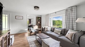 Un salon spacieux avec une grande fen être, un canapé, une table basse et une bibliothèque.