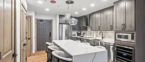 Una cocina moderna con una isla central, electrodomésticos de acero inoxidable y armarios de madera oscura.