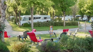 Un camping con vehículos recreativos, mobiliario exterior y un cartel que indica los servicios.