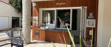 A reception area with a wooden facade, a reception desk, and a sign that reads "Réception".