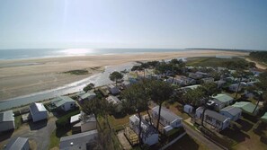Een kustgebied met een strand, een kleine nederzetting met compacte woningen en een helder uitzicht op de oceaan.