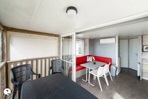 Een kamer met een tafel en stoelen, een rode bank en een schuifdeur die naar een andere kamer leidt.