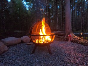 Bålsted i et skovområde med sten og et træ i nærheden.