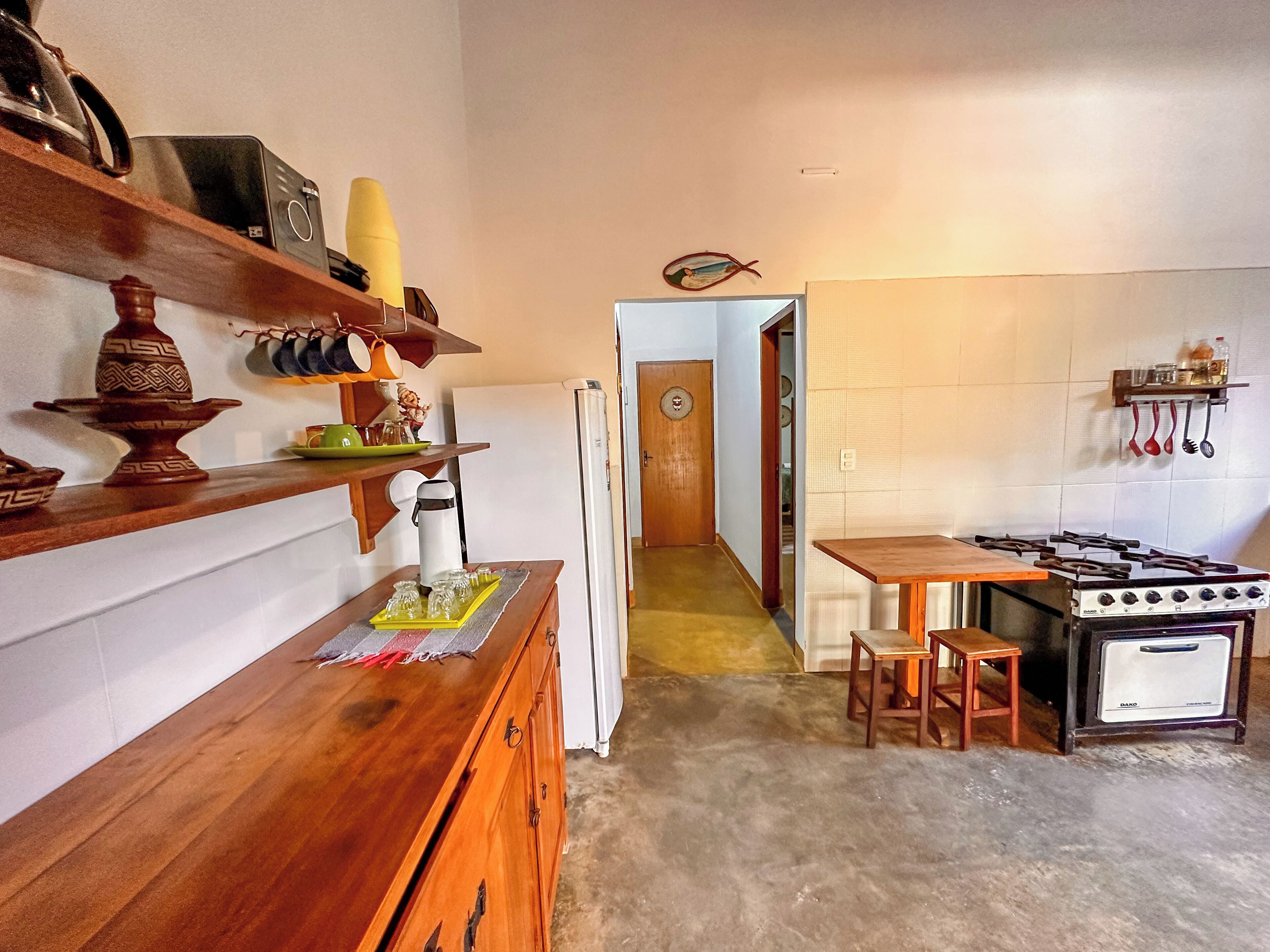 A compact kitchen with a stove, wooden cabinets, and a refrigerator.