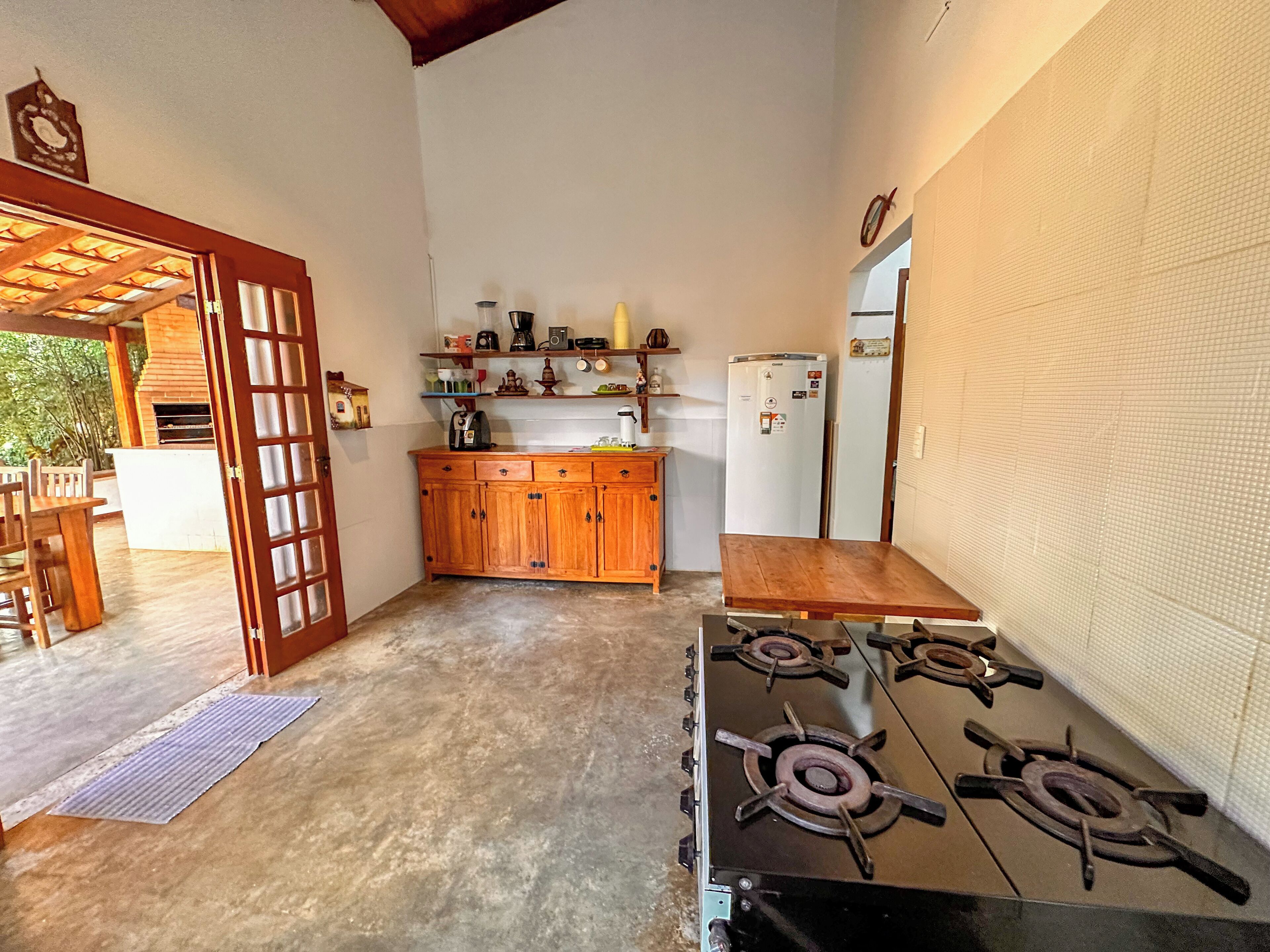 Una cocina compacta con estufa a gas, armarios de madera, refrigerador y un pequeño comedor con mesa y sillas.