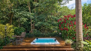Un jacuzzi rodeado de vegetación exuberante y una terraza de madera.