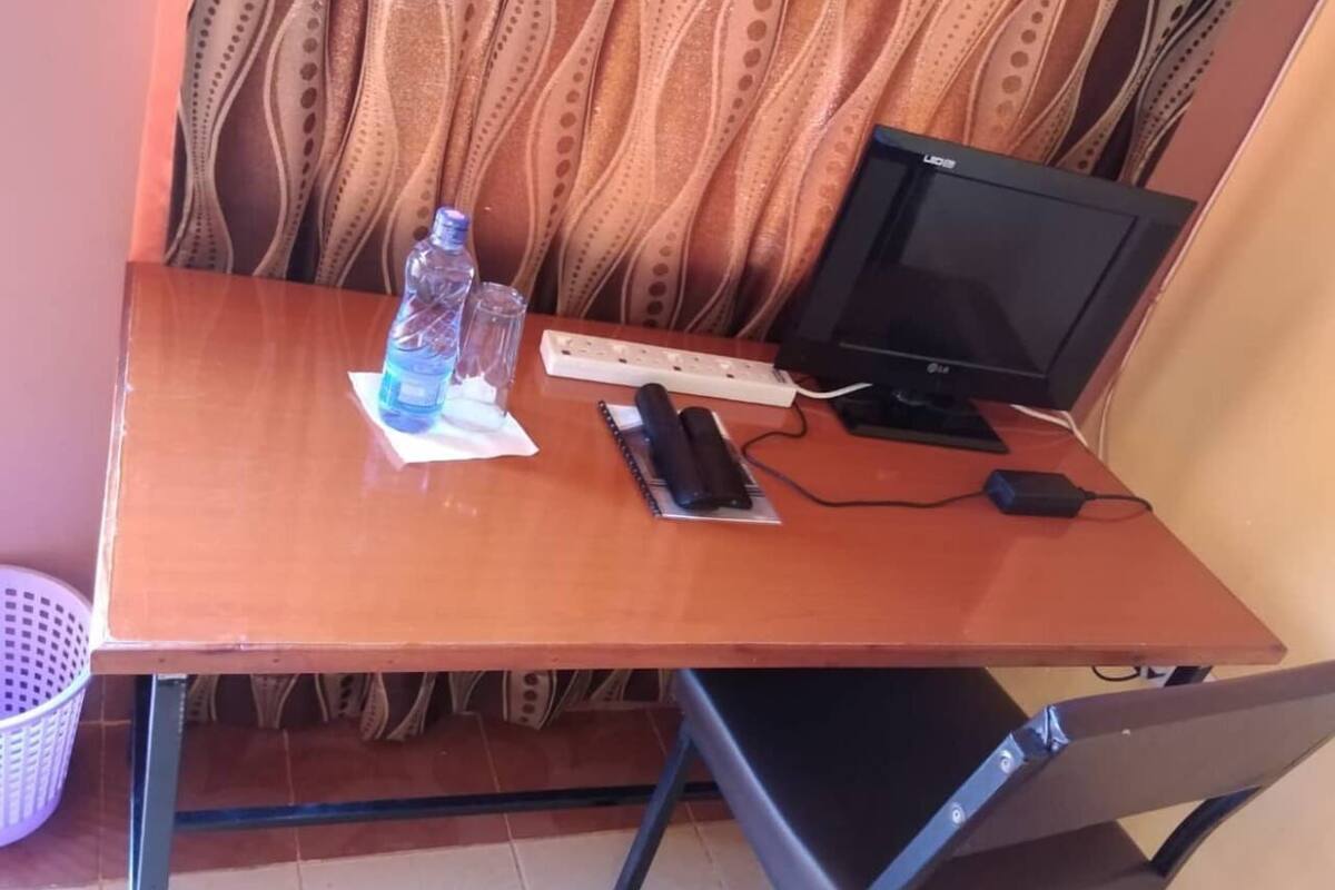 Un bureau en bois avec un écran d’ordinateur, un clavier, une souris et une bouteille d’eau.