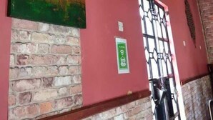 A brick wall with a painting of a tree and landscape, a door with a metal gate, and a green sign indicating Wi-Fi availability. - Acacia Shade Hotel and Gardens (Mutomo)