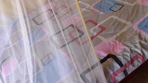 A bed with a patterned bedspread and a sheer canopy. - Acacia Shade Hotel and Gardens (Mutomo)