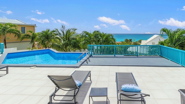 A pool area with lounge chairs and a view of the ocean. - Newly Renovated apartment with swimming pool and ocean view #3 (Pelican key)