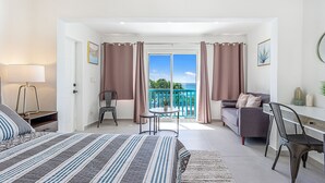 A bedroom with a bed, a desk, a chair, a sofa, and a balcony with a view. - Newly Renovated apartment with swimming pool and ocean view #3 (Pelican key)