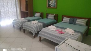 Una habitación con tres camas individuales, un armario y un cuadro en la pared.