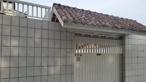Una entrada con reja, un muro de azulejos y un tejado con tejas.