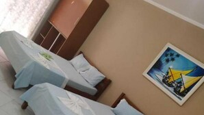 Una habitación de hotel con tres camas individuales, un armario y un cuadro en la pared.