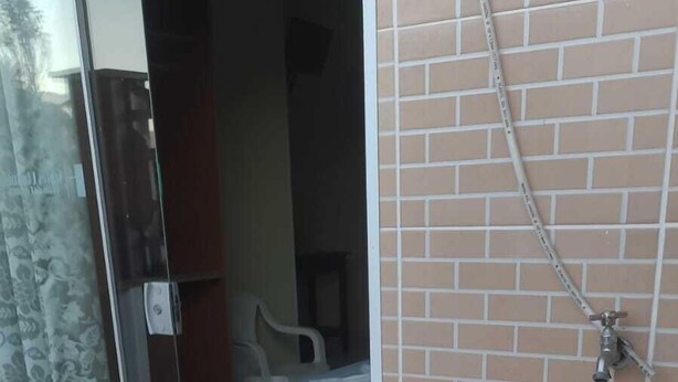 A bathroom with a sink, a shower, and a glass door leading to a bedroom. - Suites Ubatuba Praia da Lagoinha (Ubatuba)