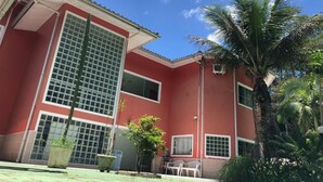 Un edificio rojo con ventanas amplias y una palmera en primer plano.