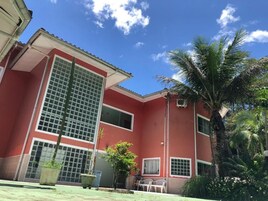 Um edifício vermelho com janelas amplas e uma palmeira em primeiro plano.