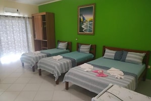 A room with three single beds, a wardrobe, and a painting on the wall.