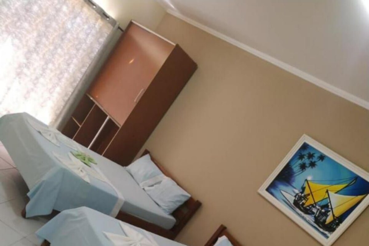 Una habitación de hotel con tres camas individuales, un armario y un cuadro en la pared.