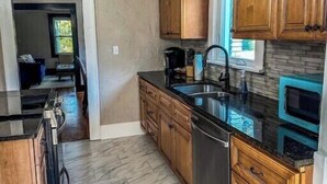 Una cocina con armarios de madera, encimera negra y suelo de baldosas.