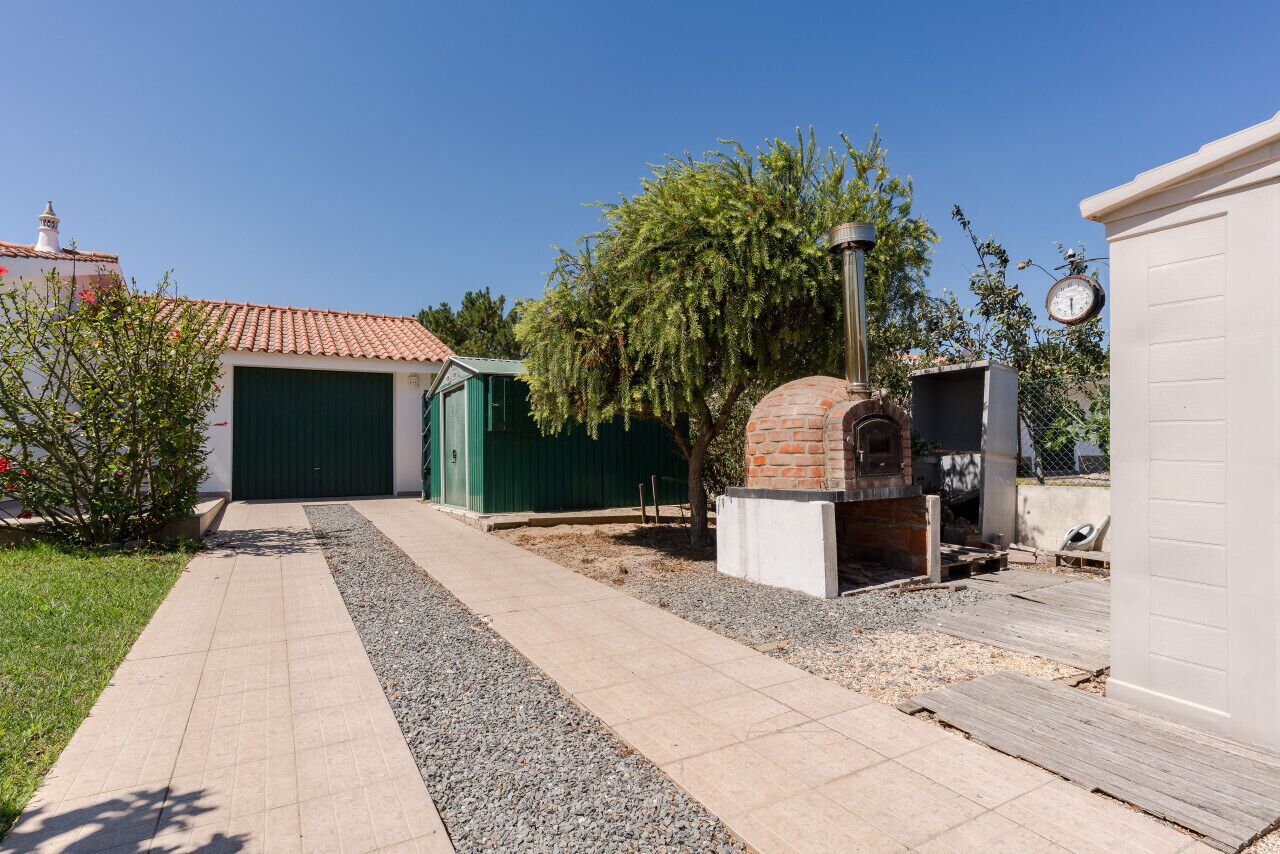 Zona de pati amb un forn de rajola, una porta verda i un camí ben definit.