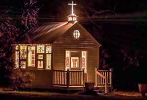 A small church with a cross on the roof, stained glass windows, and a wooden porch.