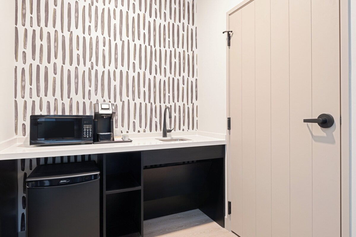 A compact kitchenette with a microwave, coffee maker, and a sink.