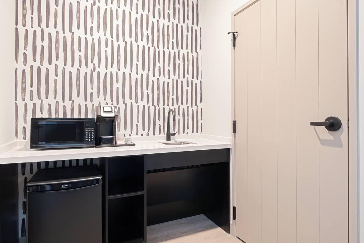 A compact kitchenette with a microwave, coffee maker, and a sink.