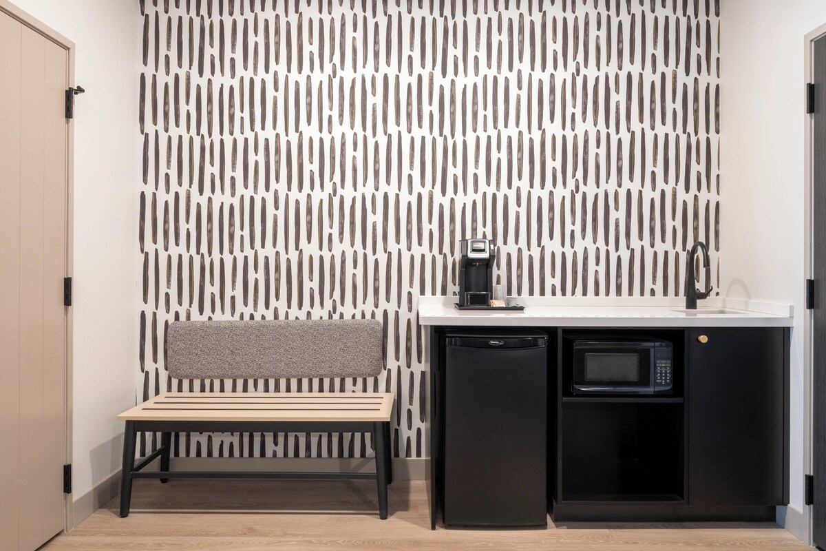 A compact kitchenette with a microwave, coffee maker, and a small sink.