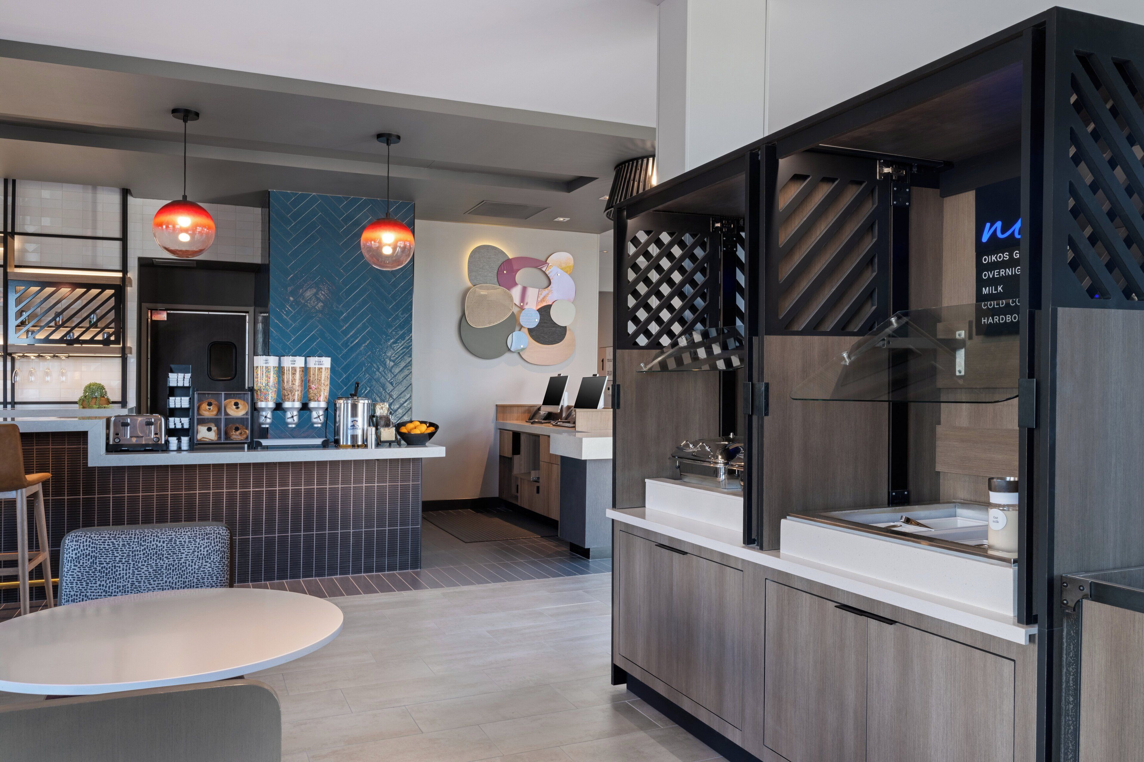 Una cocina moderna con una isla central, iluminación colgante y una pieza de arte decorativo en la pared.