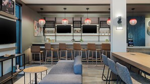 A modern bar area with seating, a TV, and a bar counter. - Atwell Suites Kansas City Airport by IHG (Kansas City)