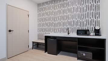 A modern kitchen with a microwave, coffee maker, and a safe.