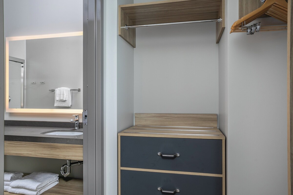 Un baño moderno con tocador de madera, un lavamanos y un espejo.