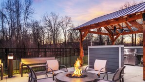 Une terrasse avec un foyer extérieur, des sièges et un espace barbecue.