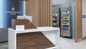 Un área de recepción con un escritorio, una computadora, un refrigerador lleno de bebidas y un letrero para la tienda E-Press.