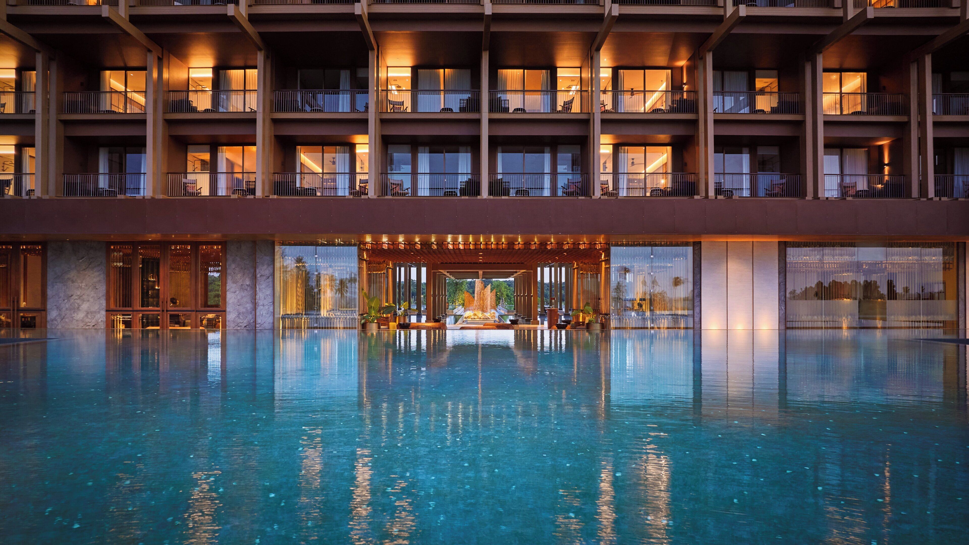 Un hotel con una amplia piscina cubierta, varios balcones y vistas del paisaje circundante.