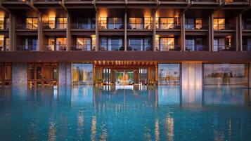 Un hotel con una amplia piscina cubierta, varios balcones y vistas del paisaje circundante.