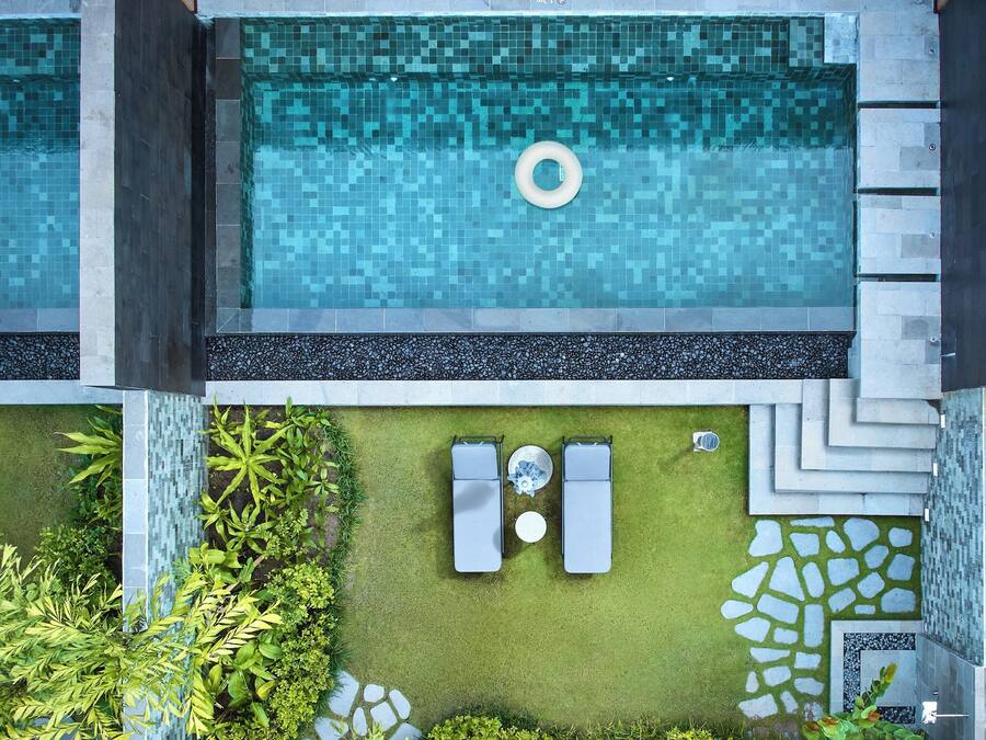 A rooftop pool with a floating ring, surrounded by lounge chairs and a pebble-patterned border.