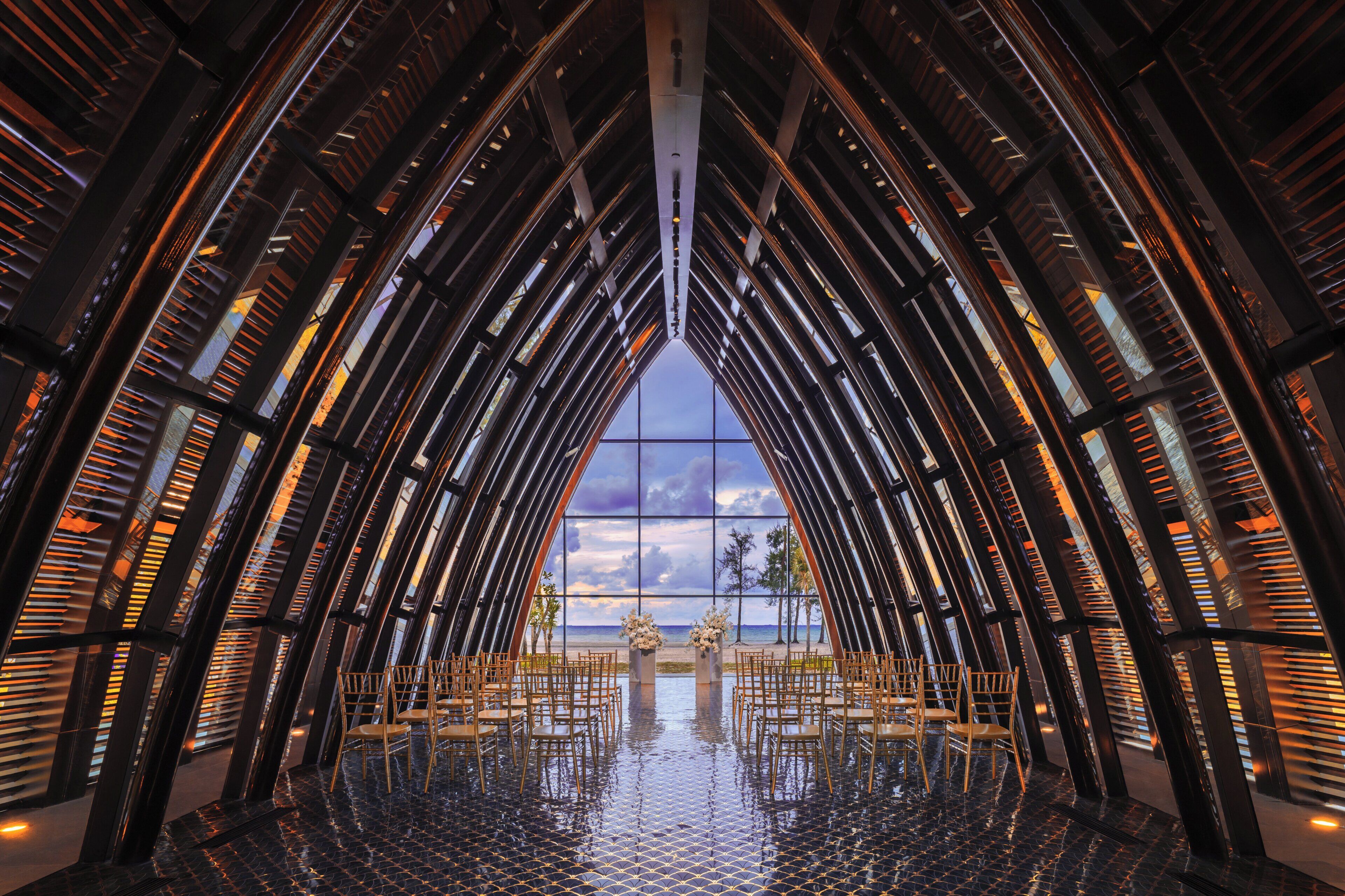 A modern interior with a central open space, surrounded by high ceilings and reflective surfaces.